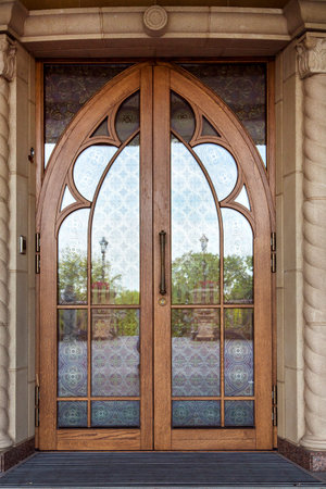 The front door on the facade of the building is wooden brown frame with glass inserts with a...