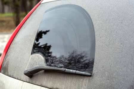 Rear window side view of a dirty car with a wiper.