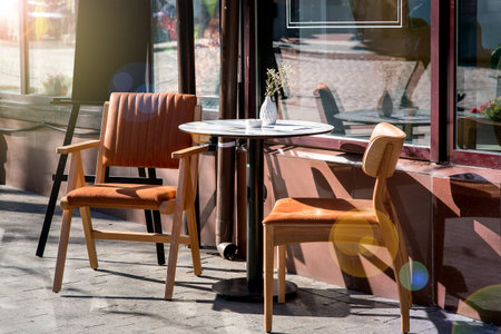 a round table with two chairs with backs on the wooden legs of a summer cafe on the sidewalk near...