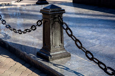 black iron column with chains on the background of marble tiles, nobody.の写真素材