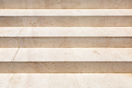 Marble staircase with stone beige steps close up detail of architecture lit by sunlight.