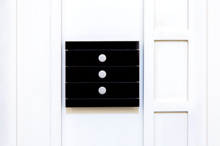 Black glass multifunctional light switch with three touch buttons mounted on a white wooden wall,...
