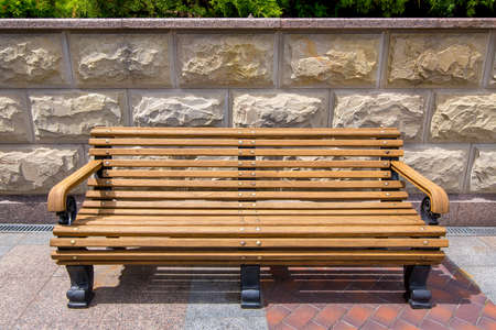 wooden bench with iron legs on the tile and on the stone wall with rustic elements.の写真素材