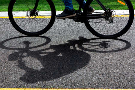 asphalt bike path with yellow markings with a passing black bike blurred in motion on summer sunny day, sports background on a bicycle theme close up.の写真素材