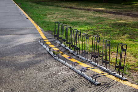 bicycle parking iron frame on an asphalt road by the side of green grass.