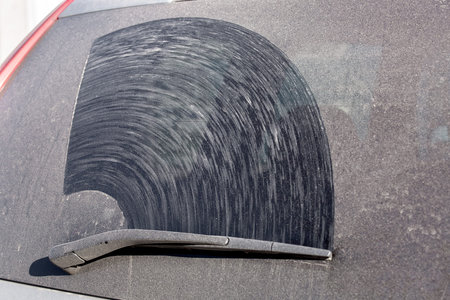 hatchback back window of a dirty car in a layer of dust and dry dirt, close up of a dirty vehicle...