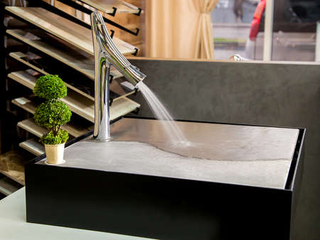 modern faucet with diffuser for bathrooms with flowing water and a tap at a presentation in the store, close up.の写真素材