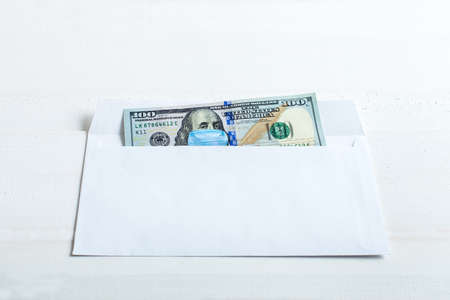Cash on medical mask in an envelope, the denomination on a table from white wooden boards with copy space, concept medical finance theme.の写真素材