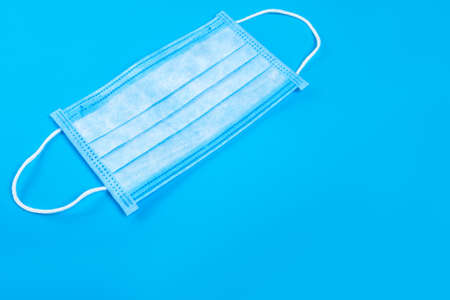 protective medical sick mask, object of health care and protection against the coronavirus virus covid 19 on a blue background with copy space.の写真素材