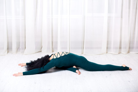 girl in sportswear doing yoga exercises lying on the floor in the room during quarantine stay home...