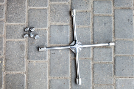a cross wrench with different sizes of heads for loosening wheel nuts, a tool for car service lies...