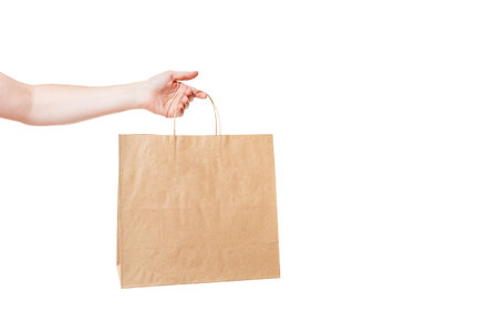 hand holds brown eco friendly craft paper bag, label packet for grocery delivery and merchandise...