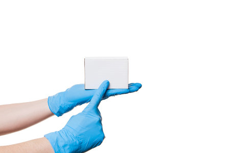 hands in blue sterile latex gloves holds white unlabel cardboard box on palm and shows a finger on...