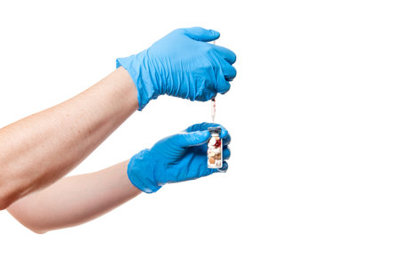 hands in blue medical gloves are holding a glass bottle with a vaccine different pills a drug into...