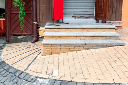 Brick threshold on the slope with granite steps to the open wooden entrance door, closeup of...