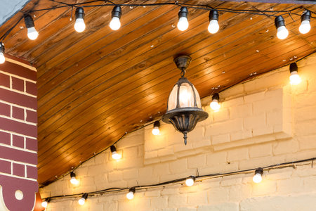 iron hanging on the ceiling retro lantern with a light bulb on the facade of a building decorated...