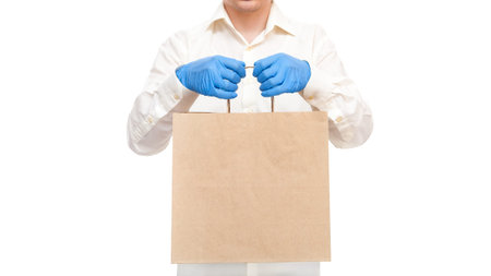 faceless deliveryman hold in hands in sterile gloves of courier for safe delivery food in un label...