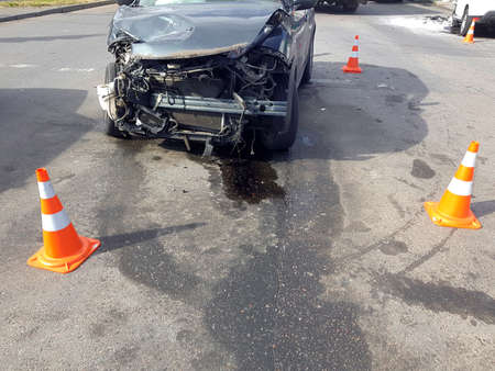broken suv car after front collision damaged engine compartment of vehicle fenced by orange traffic cones drips of spilled oil from the engine, nobody accident on sunny day.の写真素材