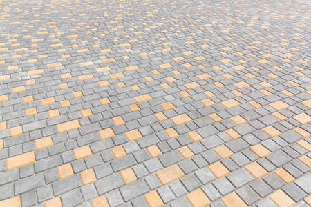 paving stone tiles of square and rectangular shape of gray and yellow are paved in perspective, closeup of the road surface.の写真素材