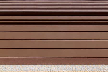 architecture brown facade of building with rustication and stripes with protective layer from moisture and water along the bottom of facade along the pedestrian walkway made of stone tiles, nobody.の写真素材