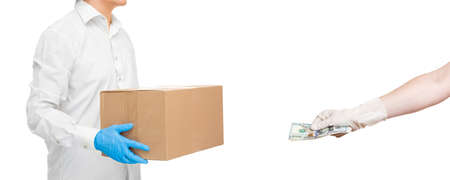 deliveryman hands in sterile gloves of courier cardboard box and hand holds out money to pay for food delivery during quarantine of social distance pandemic isolated on white background mockup view.の写真素材