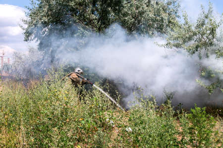 fireman in a protective suit in a cloud of smoke under burning pressure burning garbage in a natural landfill environment.の写真素材