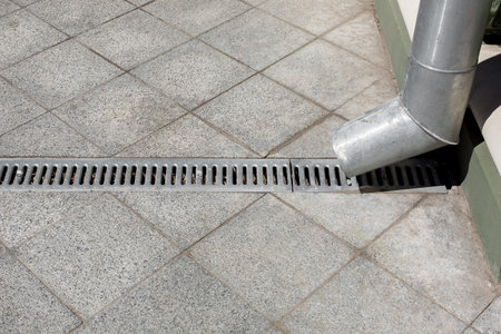 an engineering city improvement a downspout with a drainage grate against a background of a gray...