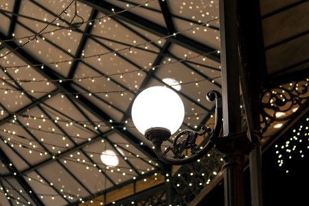 white round lantern on a wrought iron pillar of the restaurant terrace gazebo with garlands on the...