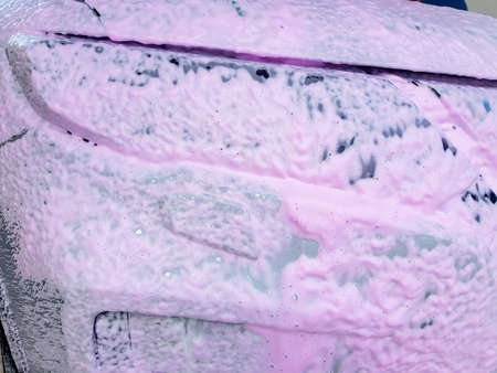 vehicle headlight covered with a layer of active white foam with pink wax, car wash and car body care.の写真素材