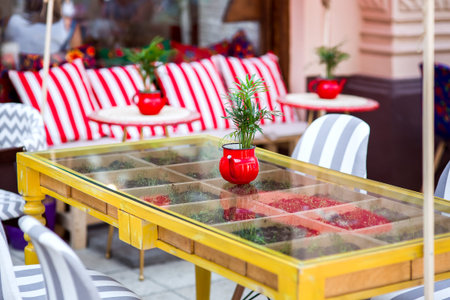 A red teapot flowerpot with a green plant on a glass table inside grows micro greens