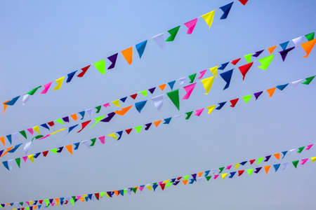 triangular holiday multi colored flags are suspended on a tight string outdoors park against the background of the sky, nobody.の写真素材
