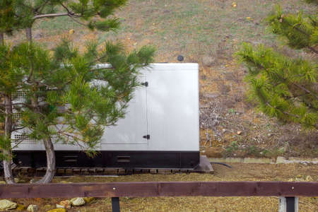 backup generator of standby power in case of power outage, installed outdoors on clay soil near pine trees, nobody.の写真素材