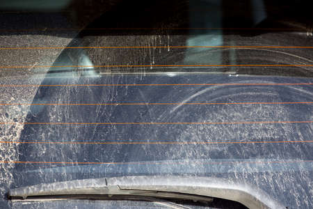 rear window of a dirty car with a windshield wiper covered with a layer of dry dust rear view of a vehicle after off road travel close-up nobody.の写真素材
