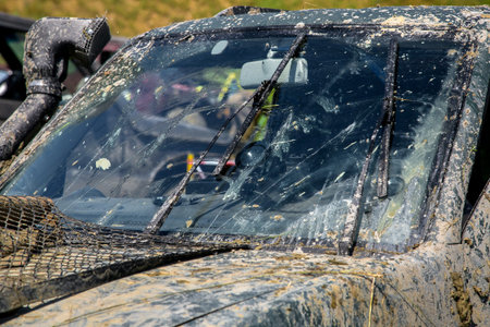 windshield wipers with washers clean the windshield from the swamp, a dirty SUV car, smeared with...