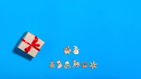 Christmas greeting card with wooden figurines on theme of new year celebration and gift box packed...