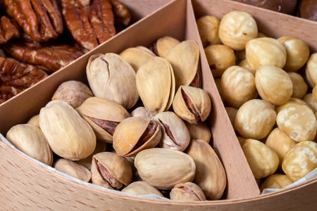 wooden box with cells for different nuts food for healthy protein nutrition close-up pistachio nut,...