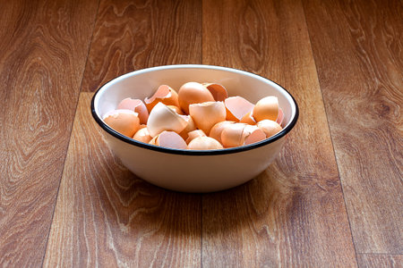 an iron bowl with eggshells stands on a wooden table top of a brown table, the remains of used...