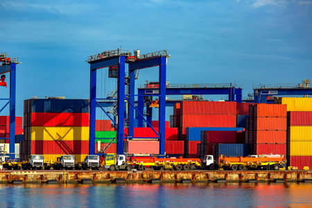 Truck in container depot in import and export area at port near sea on warehouse colore marine containers with crane for loading freight on sunny day, nobody.の写真素材
