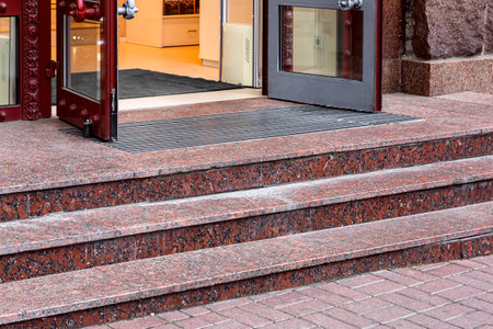 red marble staircase with granite steps to entrance door on store with glass, threshold with doormat at facade of building on retro style side view closeup, nobody.の写真素材