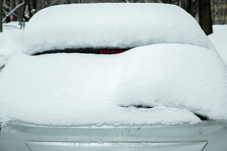 rear window with windshield wiper, washer and brake light covered with a large layer of snow on a winter cold day.の写真素材