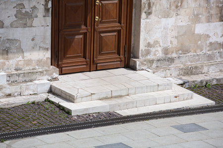 brown wooden entrance door of an white old stone building on a sunny day, close-up architecture of the old city, nobody.の写真素材