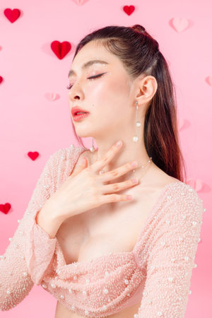 Valentine concept. Young Asian sexy woman gathered in ponytail with natural makeup on face have plump lips and clean fresh skin on pink heart pattern background.の写真素材