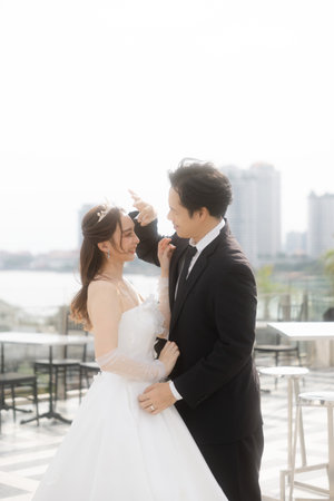Lovely Asian bride looking at her groom feel in love on the rooftop in a romantic outdoor hotel. Beautiful couple in wedding attire.の写真素材