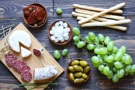 Italian bruschetta made with toasted slices of bread with olives, cherry tomatoes and  olive on a  Board over dark wooden backgroundの写真素材