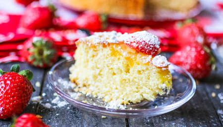 Lemon cake with strawberries, sugar end chocolate over an old wooden table with decorative napkins.の写真素材
