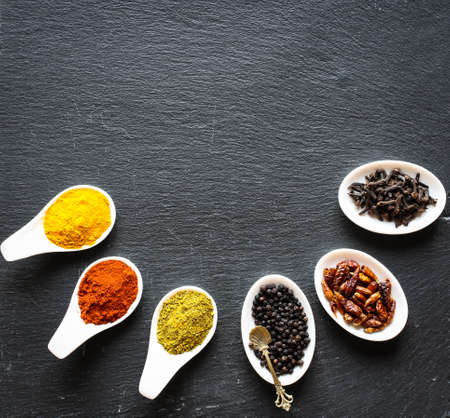 Spices in the spoons over a black stone tableの写真素材