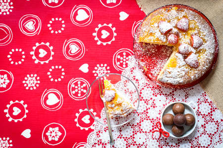 Lemon cake with strawberries, sugar end chocolate over an old wooden table with decorative napkins.の写真素材