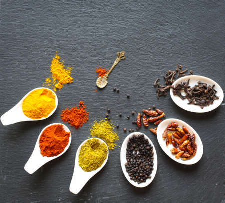 Spices in the spoons over a black stone tableの写真素材