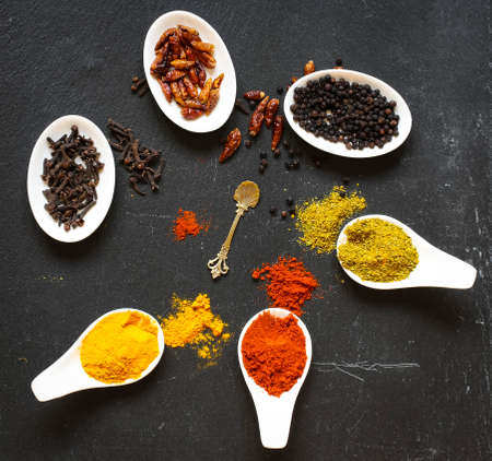 Spices in the spoons over a black stone tableの写真素材