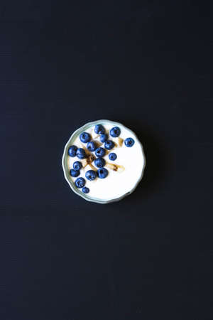 Healthy Breakfast with blueberries and banana yogurt, biscuits, marmalade, coffee and peaches over a light wooden background.の写真素材